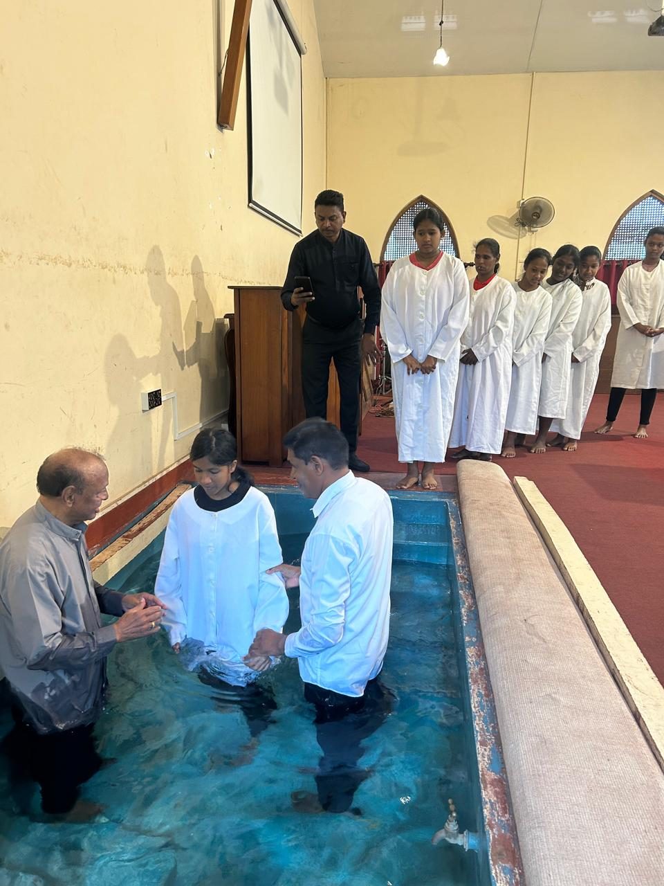 New believers in white robes waiting to be baptized at Hamel Sonu's church in Pakistan