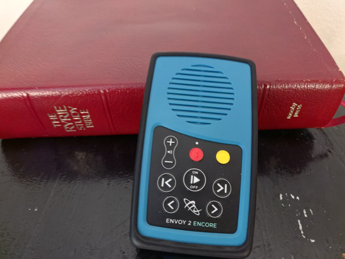 A MegaVoice player beside a study Bible, smaller than the Bible itself