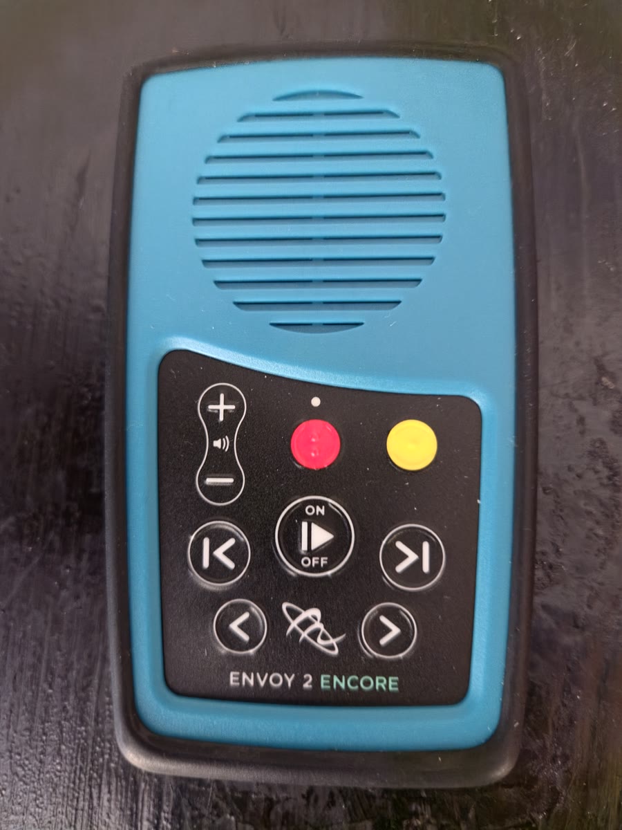 A MegaVoice Envoy 2 Encore solar audio player, about the size of a hand